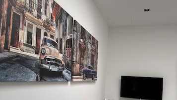 Ein modernes Wohnzimmer mit einer großen Wandmalerei, einem Flachbildfernseher und einem grauen Schrank.