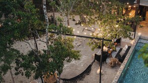 Un área de piscina al aire libre con una hamaca, asientos e iluminación con guirnaldas.
