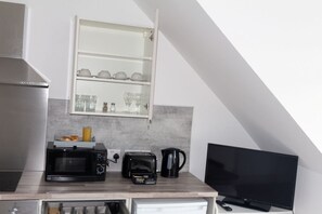 A kitchenette with a microwave, toaster, and coffee maker on a countertop.