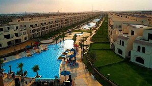 Een resort met een centraal zwembad, meerdere gebouwen en een verzorgd gazon.