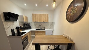Una cocina moderna con una mesa de madera, sillas negras, una estufa negra, un microondas y un fregadero.