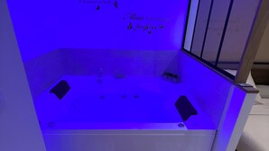 Zona de spa con hidromasaje, terraza de madera y detalles decorativos en la pared.