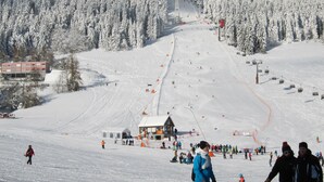 Une station de ski dotée d’un télésiège, d’arbres couverts de neige et d’un bâtiment avec un toit rouge.