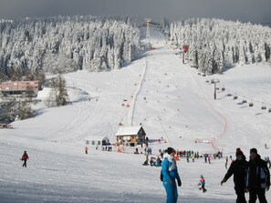 Ein Skigebiet mit Seilbahn, schneebedeckten Bäumen und einem Gebäude mit rotem Dach.