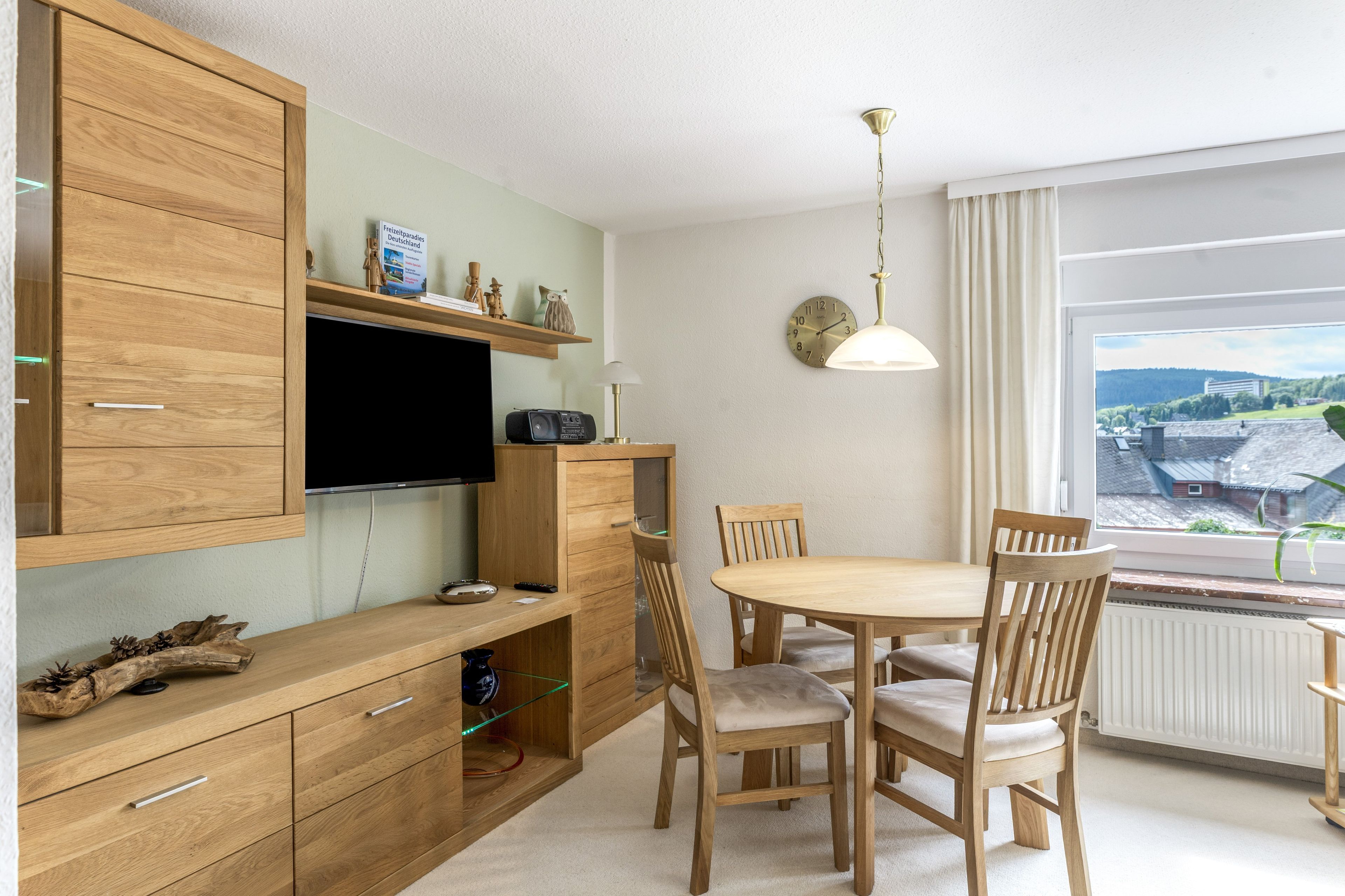 Eine moderne Küche mit Holzausstattung, einem integrierten Fernseher und einem Essbereich mit Holztischen und einem Tisch.