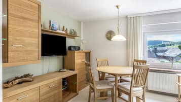Eine moderne Küche mit Holzausstattung, einem integrierten Fernseher und einem Essbereich mit Holztischen und einem Tisch.