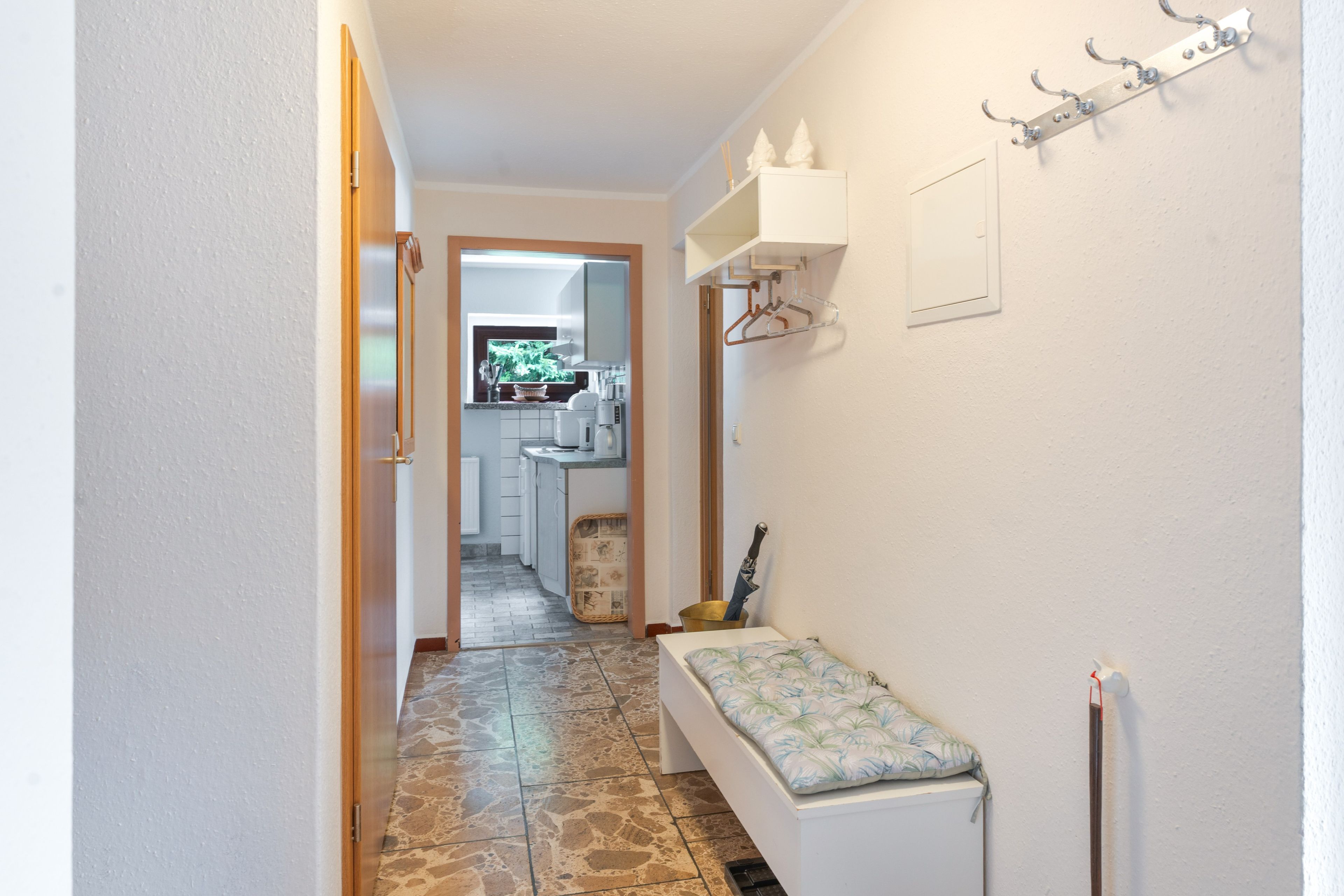 A narrow hallway with a bench, a radiator, and a coat rack.