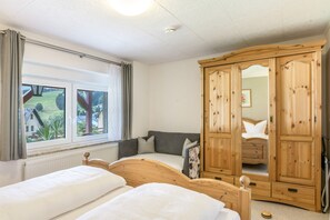 Un dormitorio con dos camas, un armario grande y una ventana con cortinas.