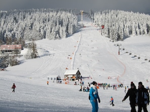 Ein Skigebiet mit Seilbahn, schneebedeckten Bäumen und einem Gebäude mit rotem Dach.