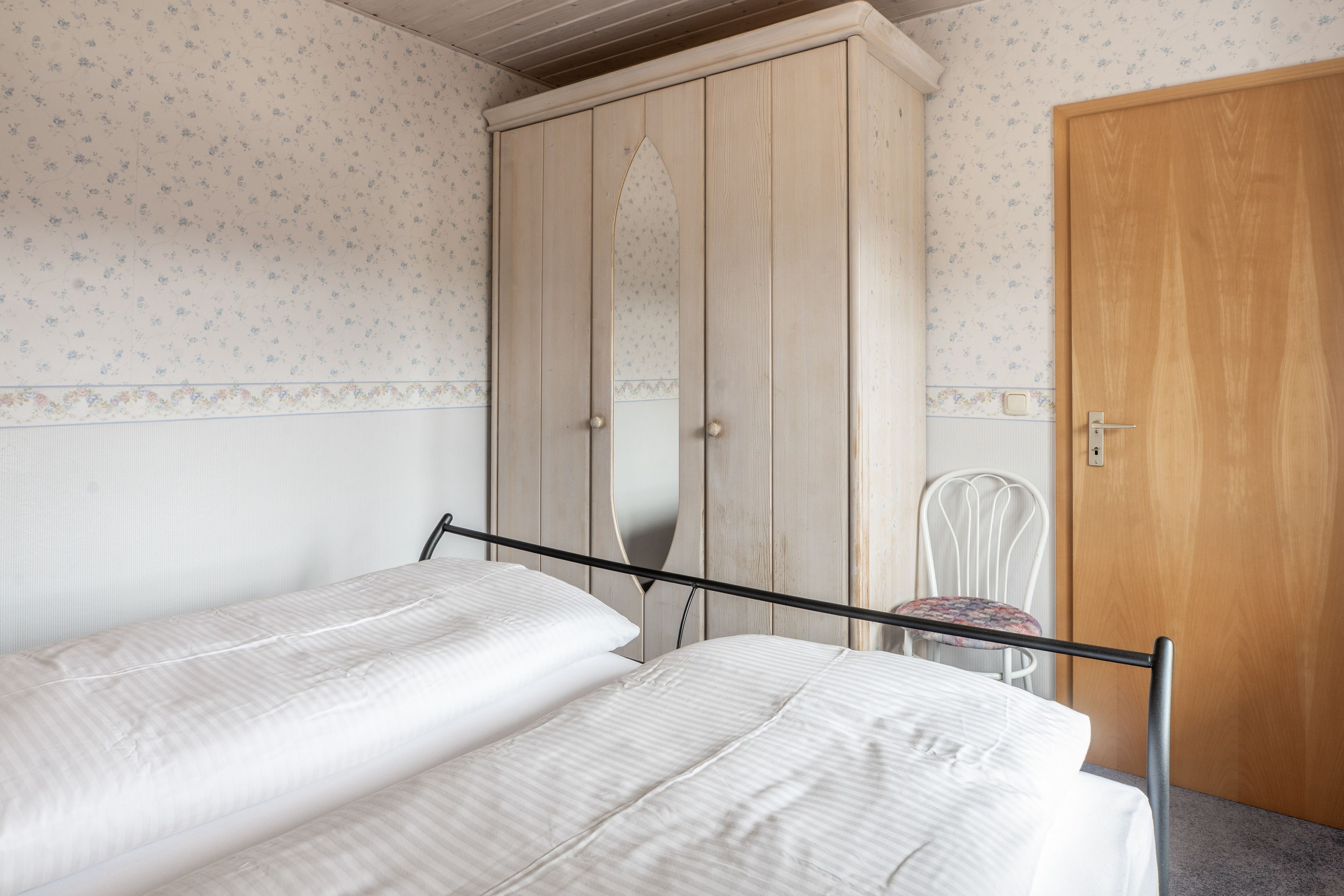 Ein Schlafzimmer mit Bett, Kleiderschrank und Stuhl.