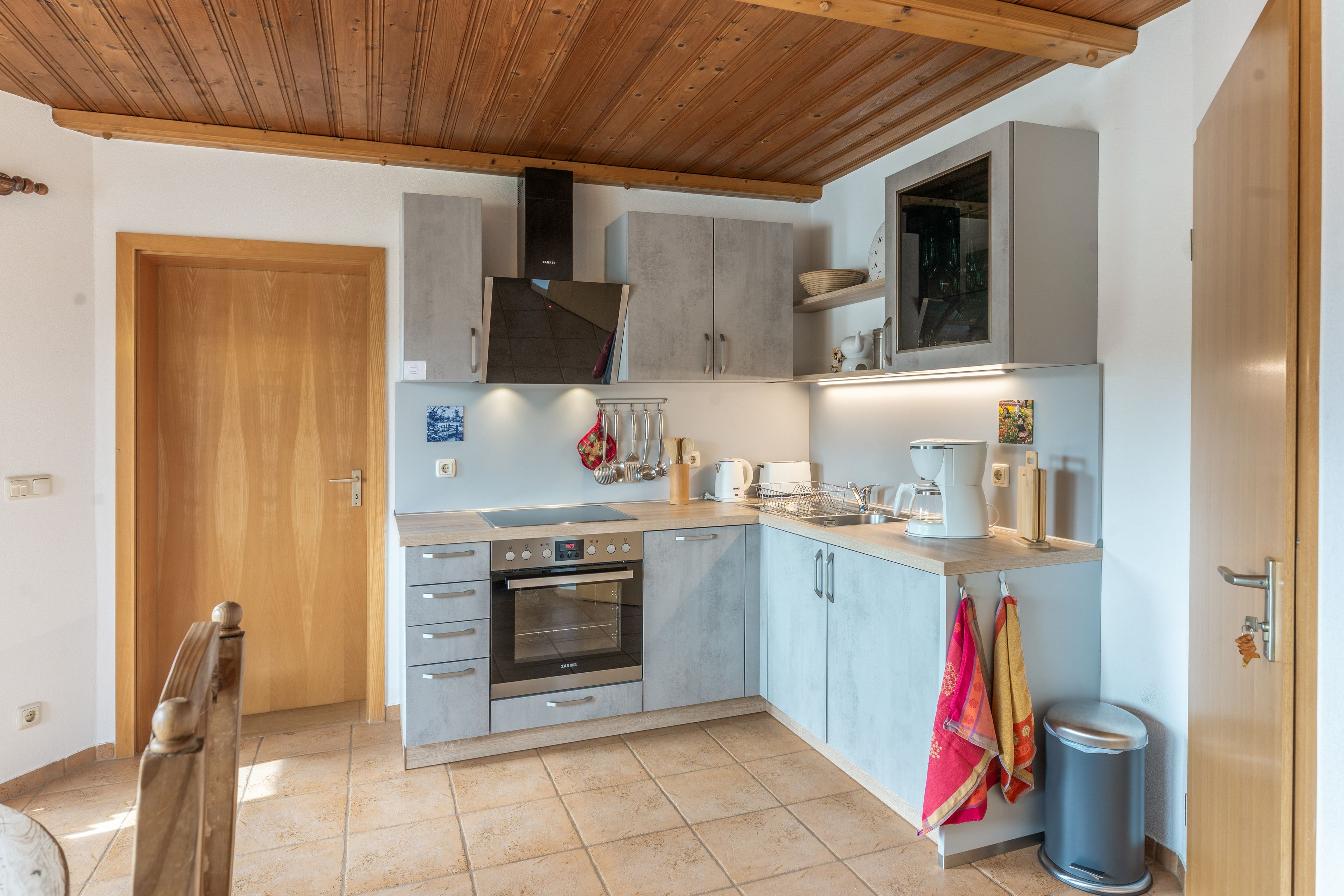 A compact kitchen with a built-in oven, a coffee maker, and a trash bin.