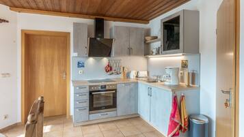 A compact kitchen with a built-in oven, a coffee maker, and a trash bin.