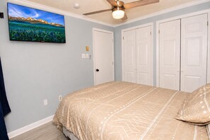 A bedroom with a bed, a ceiling fan, a wall-mounted TV, and a set of white doors. - ML 354 - Dazzling mountain views await you! Renovated bike-in/out retreat! (Snowshoe)