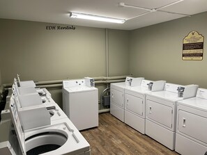 A laundry facility with multiple Whirlpool washers and dryers, a sign instructing not to put boots and shoes in washers or dryers, and a warning about dryers melting ski clothing. - ML 354 - Dazzling mountain views await you! Renovated bike-in/out retreat! (Snowshoe)