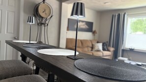 A dining table with placemats and a lamp, a clock on the wall, and a couch in the background. - My Happy Place! "RoundWeGoToo" (Machesney Park)