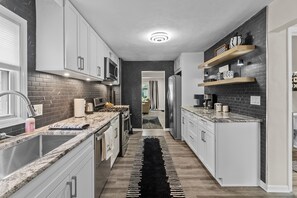 A modern kitchen with white cabinets, a black and white patterned rug, and a checkered shelf. - My Happy Place! "RoundWeGoToo" (Machesney Park)