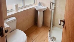Et badeværelse med toilet, håndvask og bruseniche.