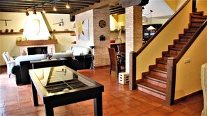 Un salón amplio con chimenea, una mesa de comedor y una escalera.