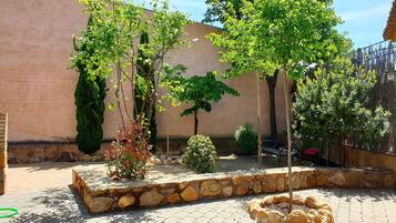 A courtyard with stone walls, a variety of trees, and a bench.