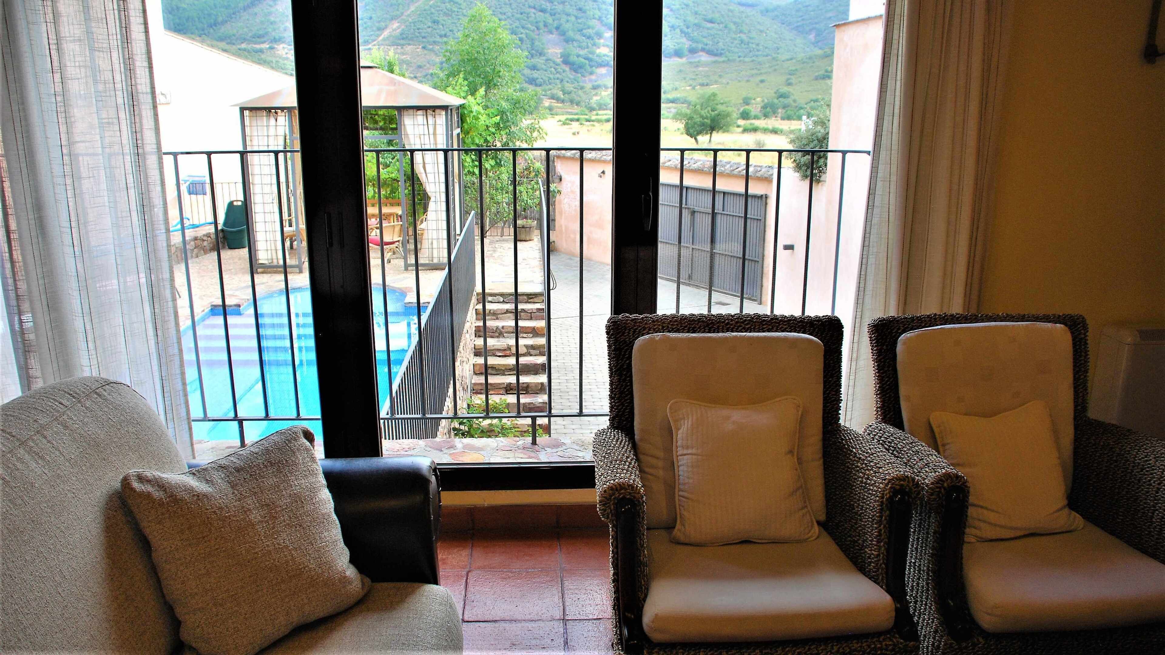 A balcony with wicker chairs and a view of a swimming pool and mountains.