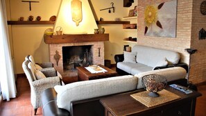Una sala de estar acogedora con chimenea, un sofá, una mesita de centro y un cuenco decorativo.