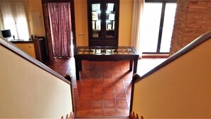 A staircase leading to a room with a tiled floor, a wooden table, and a door with glass panels.