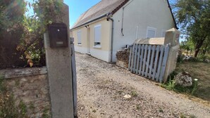 A gravel driveway leading to a building with a white exterior and a grey roof.