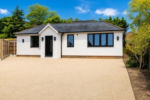 A single-story building with a flat roof, a front door, and a garage. - Brand New • Bungalow • Driveway Parking • Office (Bedford)