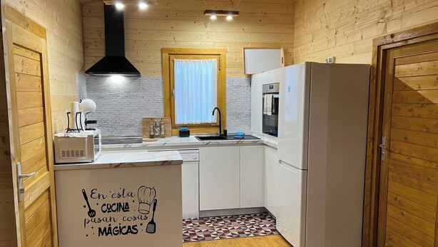 A compact kitchen with wooden walls, a white countertop, and a built-in oven. - Casa del Mar Iznájar by Ruralidays (Córdoba)