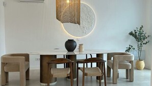 Uma sala de jantar com uma mesa redonda, quatro cadeiras, um vaso e um vaso de planta.