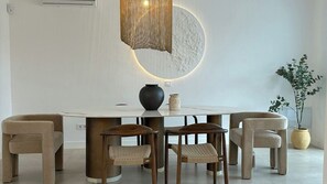Ein Essbereich mit einem runden Tisch, vier Stühlen, einer Vase und einem Blumentopf.
