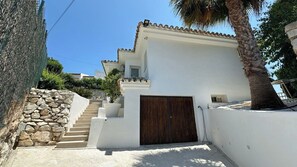 A white building with a stone wall and a wooden gate. - Luxury Villa Mijas costa by Ruralidays (Málaga)