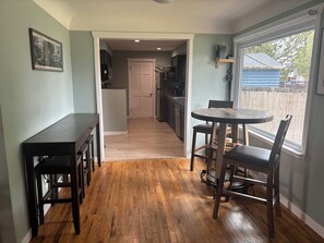 A kitchen with a wooden floor, a dining table with chairs, and a window with a view of the outside. - 3-bedroom house in charming Greeley with AC. Backyard fire pit and covered patio (Greeley)
