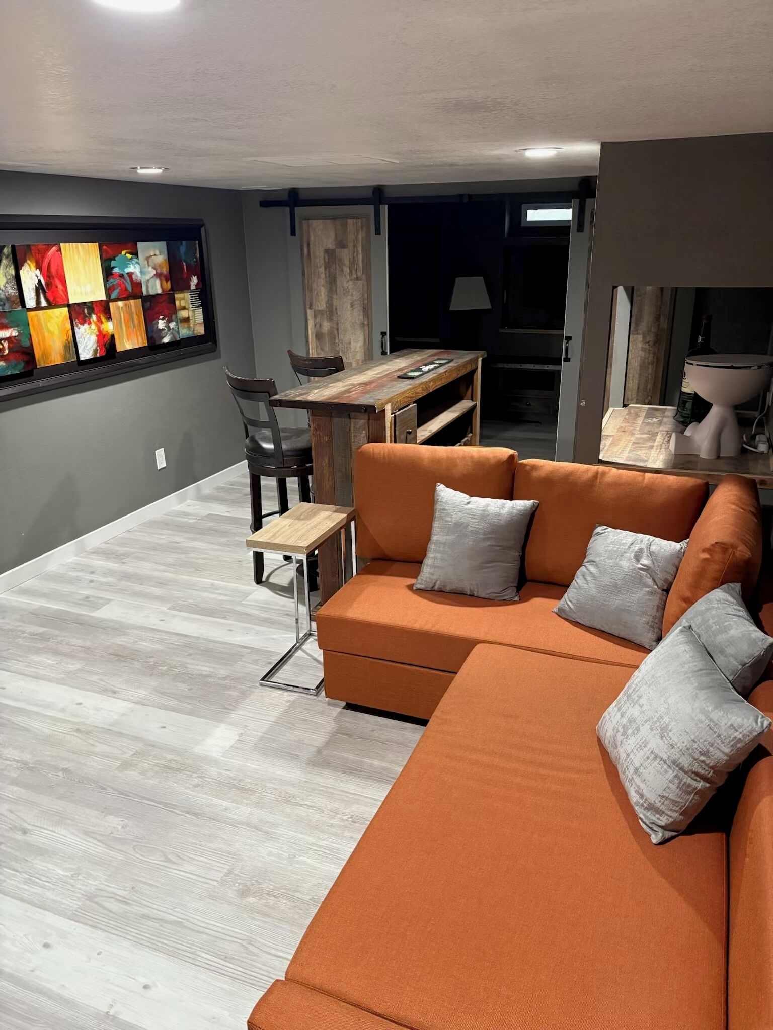 A modern living room with a sectional sofa, a small wooden table, and a dining area.