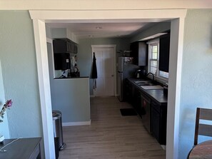 A narrow kitchen with a refrigerator, stove, and sink. - 3-bedroom house in charming Greeley with AC. Backyard fire pit and covered patio (Greeley)