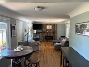 A compact living space with a dining area, a sofa, a fireplace, and a TV mounted on the wall. - 3-bedroom house in charming Greeley with AC. Backyard fire pit and covered patio (Greeley)
