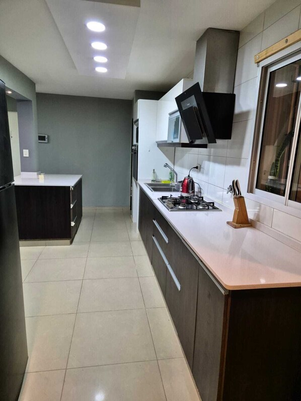 A modern kitchen with a gas stove, a microwave, and a built-in oven.