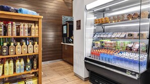 Um saguão de hotel com um posto de bebidas de serviço e uma estante repleta de artigos de higiene pessoal.