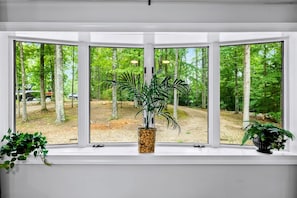 Ett rum med ett stort, utåtbuktande fönster med utsikt över ett skogsområde.