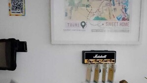 A wall with a framed map, a QR code, a vintage radio, a toy car, a bell, a lantern, and a small plant. - Sweet Home Punta Cana Guest House (Punta Cana)
