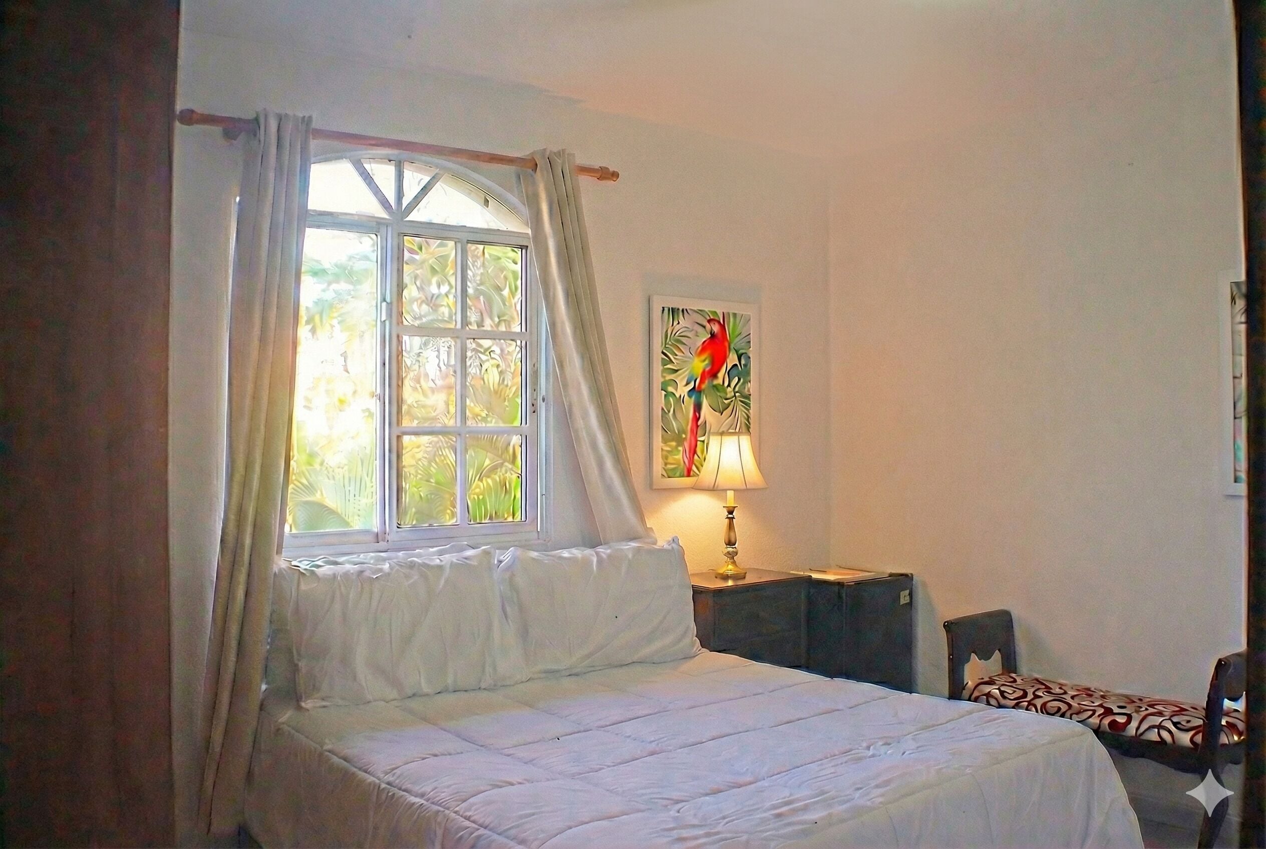 Une chambre à coucher avec un lit, une fenêtre avec des rideaux, une lampe, une chaise et un tableau accroché au mur.