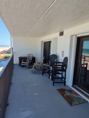 A balcony with a table and chairs, a view of the beach, and a door leading to the interior. - Beautiful Oceanfront 2/2 Condo, Private Balcony, Beachfront pool, No-Drive Beach (Daytona Beach)