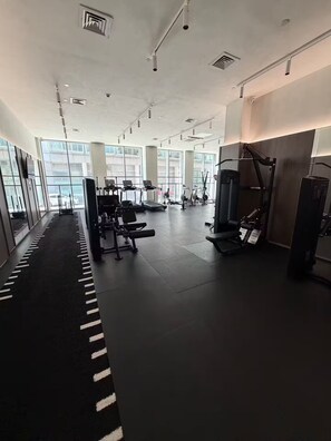 Ein Fitnessstudio mit Trainingsgeräten, großen Fenstern und einem klaren, modernen Design.