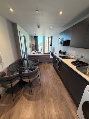A modern kitchen with a central island, built-in oven, and microwave. - Apartment 1 Bedroom (Salford)