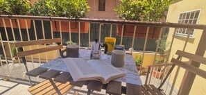 An outdoor patio with a wooden table, a book, a coffee pot, and a potted plant. - Casalù | Private Garden, Free Parking & Metro B to Downtown Rome (Roma)