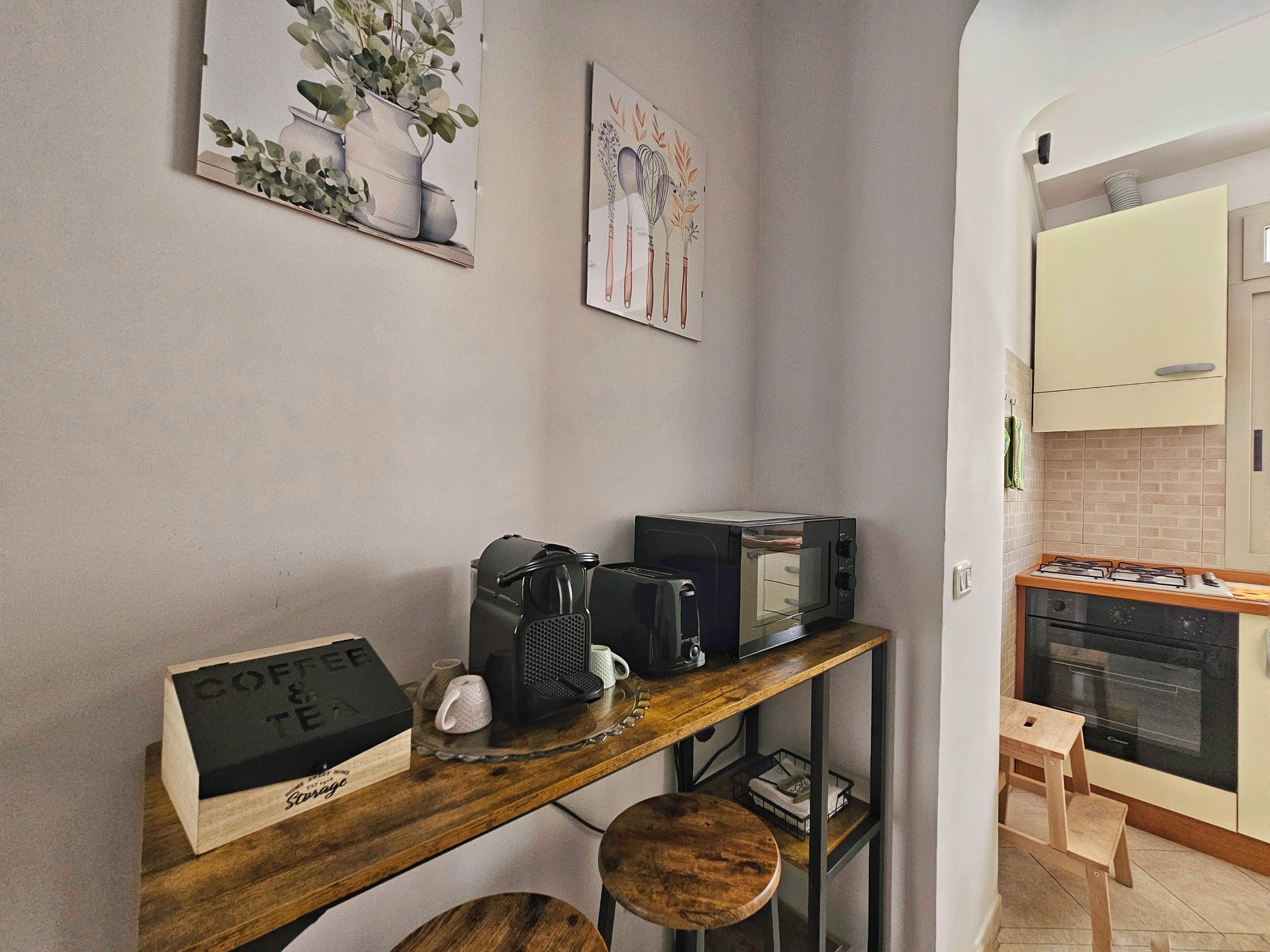 A kitchen with a wooden countertop, a coffee machine, a toaster, and a small stool.