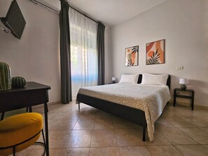 A hotel room with a bed, two bedside tables, a desk, a chair, and artwork on the wall. - Casalù | Private Garden, Free Parking & Metro B to Downtown Rome (Roma)