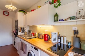Eine kleine Küche mit Waschmaschine, Kaffeemaschine und verschiedenen Küchenutensilien.