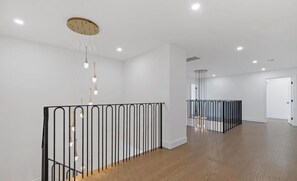 A spacious interior with a wooden floor, a black metal railing, and a ceiling with recessed lighting. - Luxury 8BR Estate Heated Pool Walk to Shuls (Long Branch)