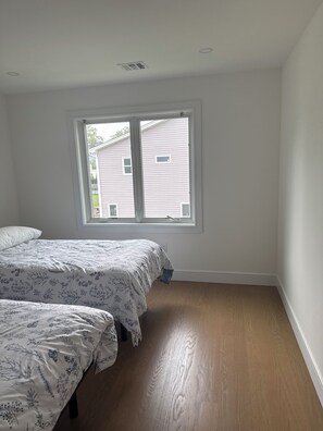 Ein Schlafzimmer mit zwei Betten, einem großen Fenster und Holzböden.